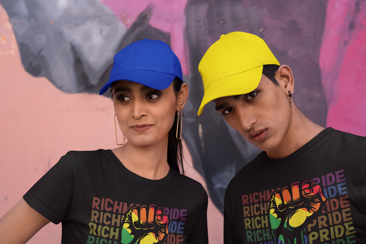 An indian sibling set, female and male, wearing Richmond Pride t-shirts and colorful baseball caps.