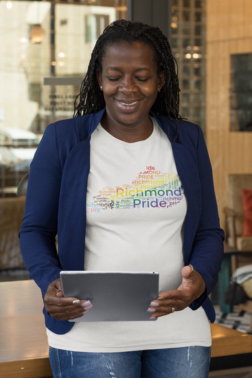 Woman looking at her tablet while wearing white Richmond Pride t-shirt in the shape of Kentucky with rainbow words of "Richmond Pride" inside.